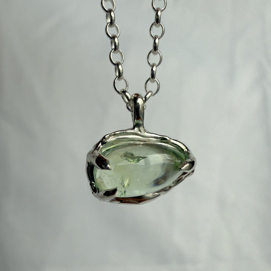 Necklace with a green tourmaline pendant on a plain background