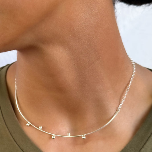 Close-up of a person wearing a delicate silver necklace and earrings.
