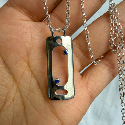 Silver pendant with blue stones held in a hand