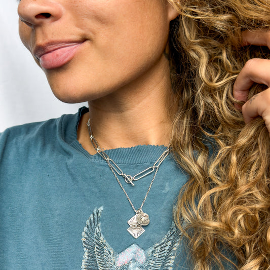 Person wearing a Harley Davidson shirt with layered necklaces