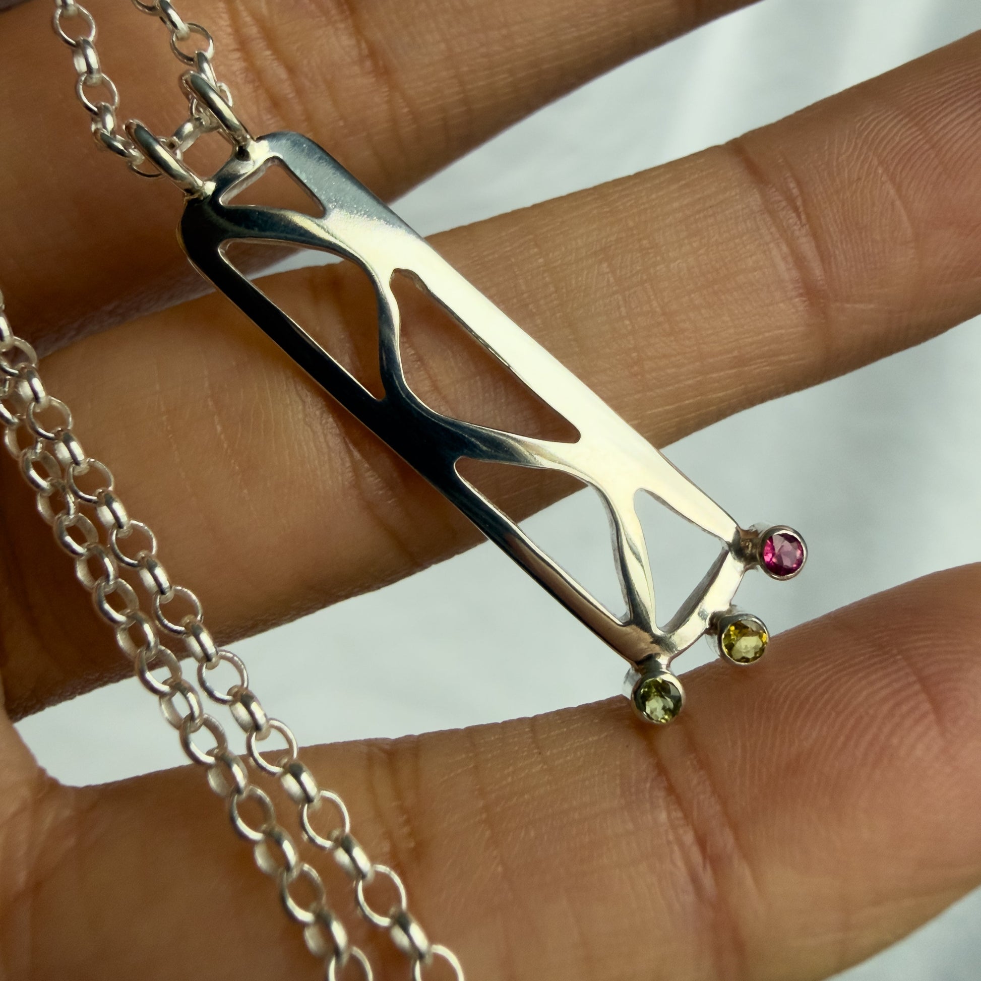 silver necklace with a unique pendant held between fingers