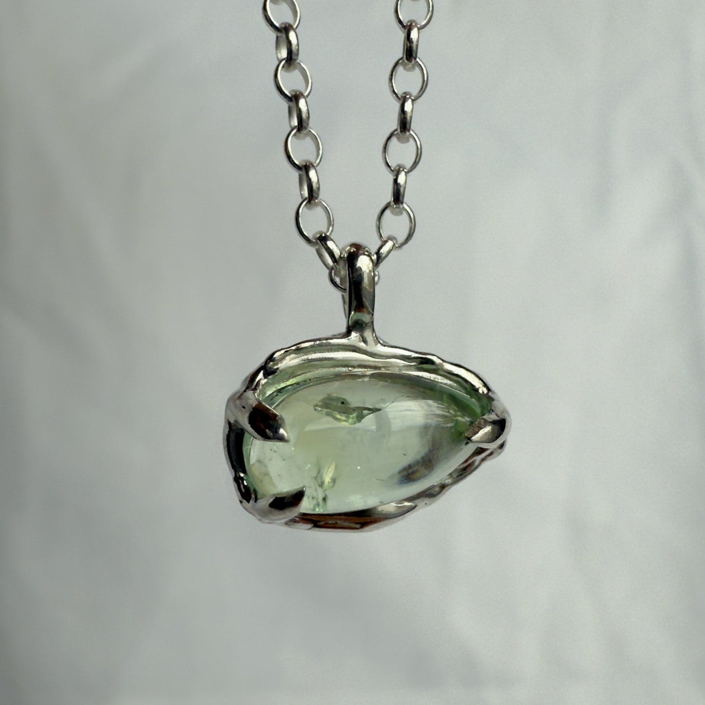 Necklace with a green tourmaline pendant on a plain background