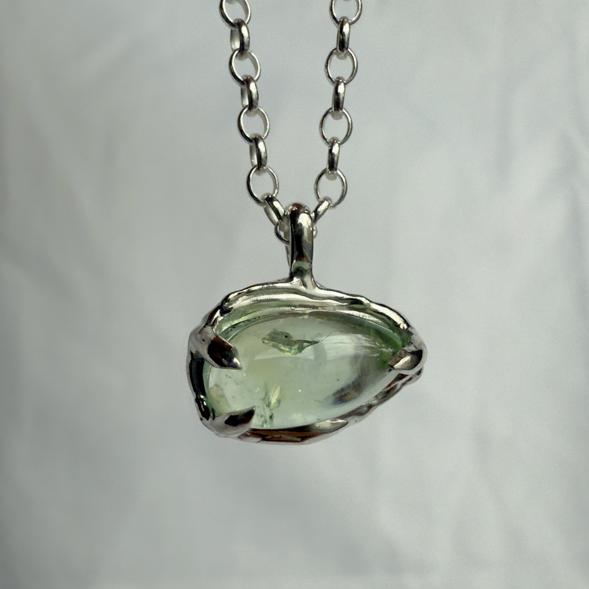 Necklace with a green tourmaline pendant on a plain background