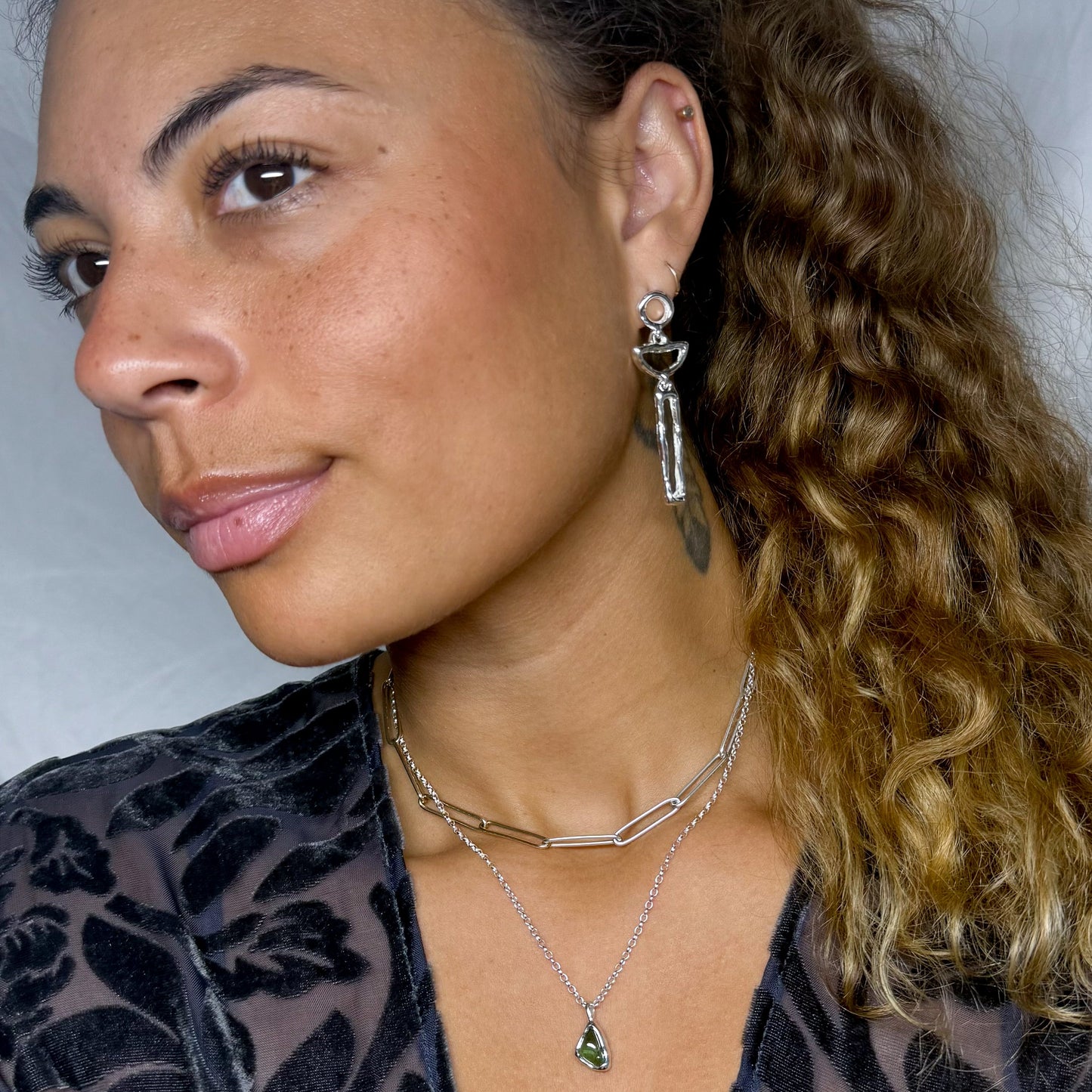 Woman with styled hair and earrings against a neutral background
